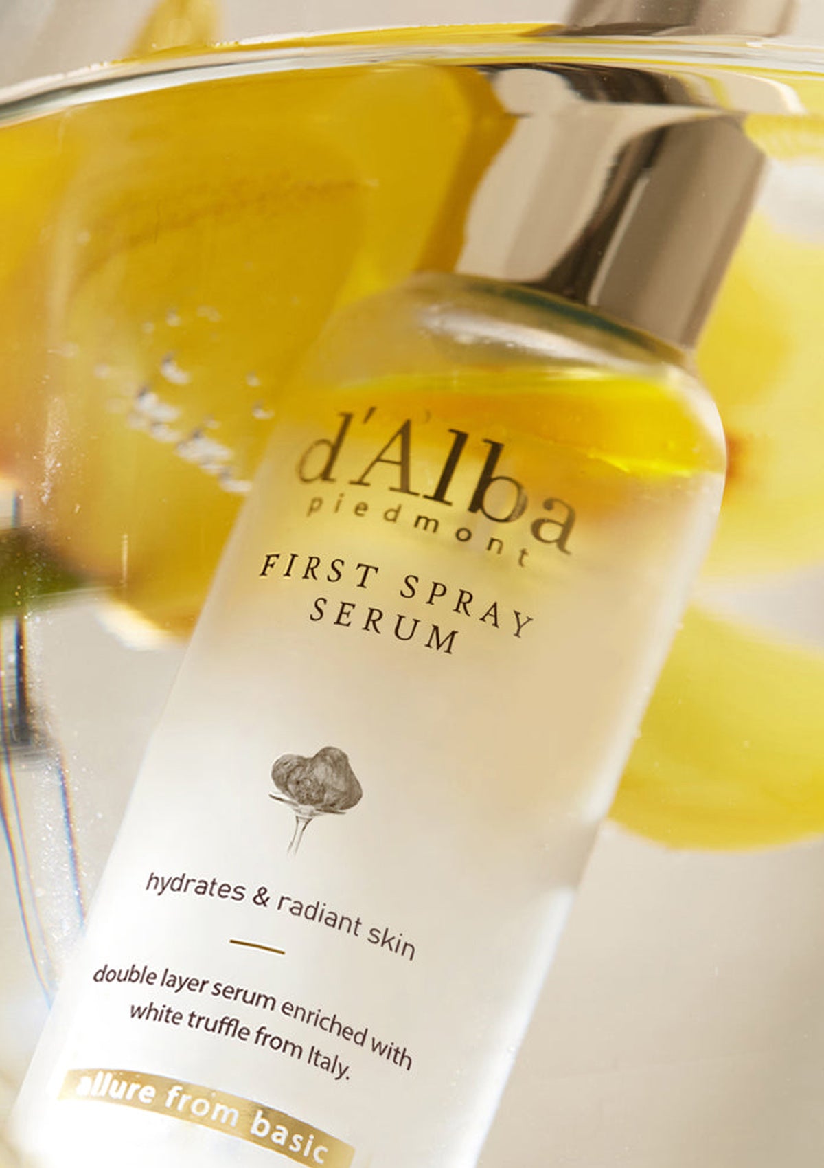 Two bottles of D'Alba White Truffle First Spray Serum, one is 50ml and the other is 100ml, both with a white label and gold accents.